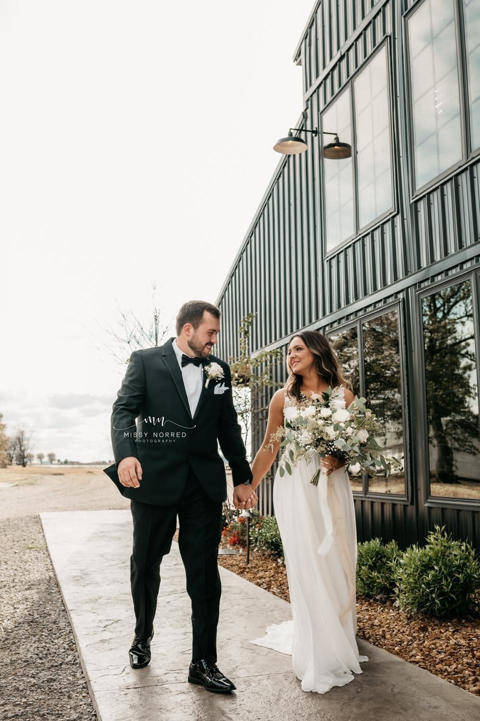 Bride and groom smiling and walking holding hands.